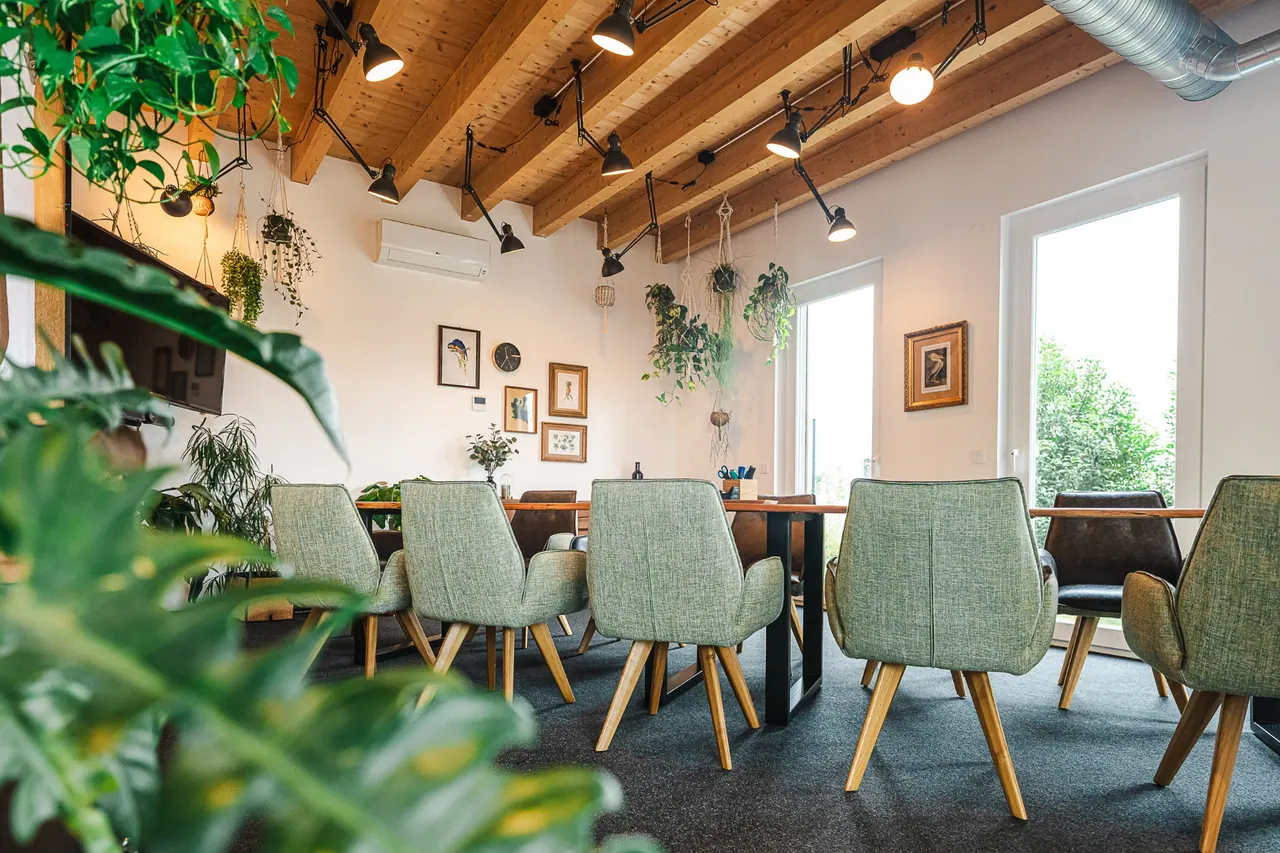 Architekturfotografie — Meetingraum mit Holzbalken, Pflanzen und langem Tisch