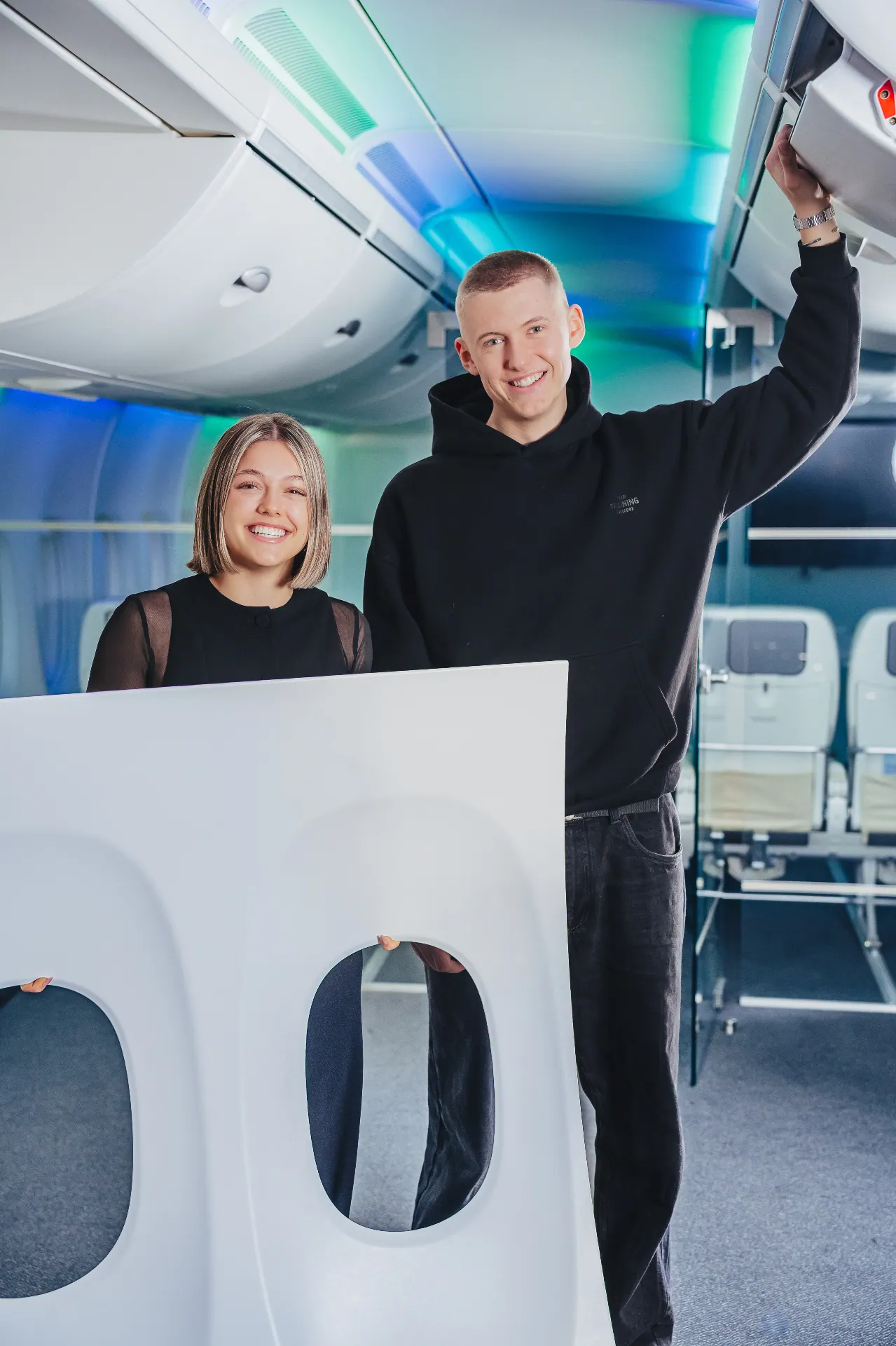 Mitarbeiterfoto — Zwei Azubis lachend in Flugzeugkabine bei Diehl Aviation