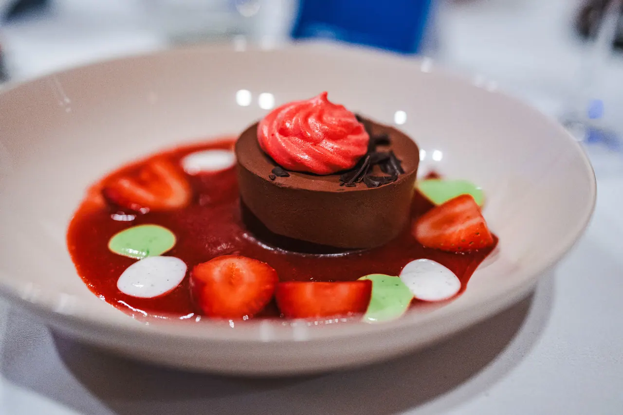 Eventfoto 3 — Schokoladendessert mit Erdbeerragout und Vanille-Spiegel auf weißem Teller