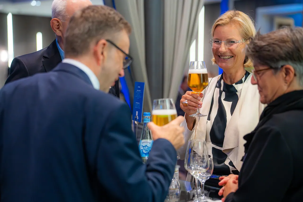 Eventfotografie — Gäste stoßen mit Bier an der Bar an
