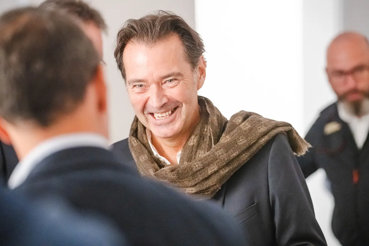 Manntech/Alimak Büroeröffnung — Lachender Gast mit Schal im Gespräch