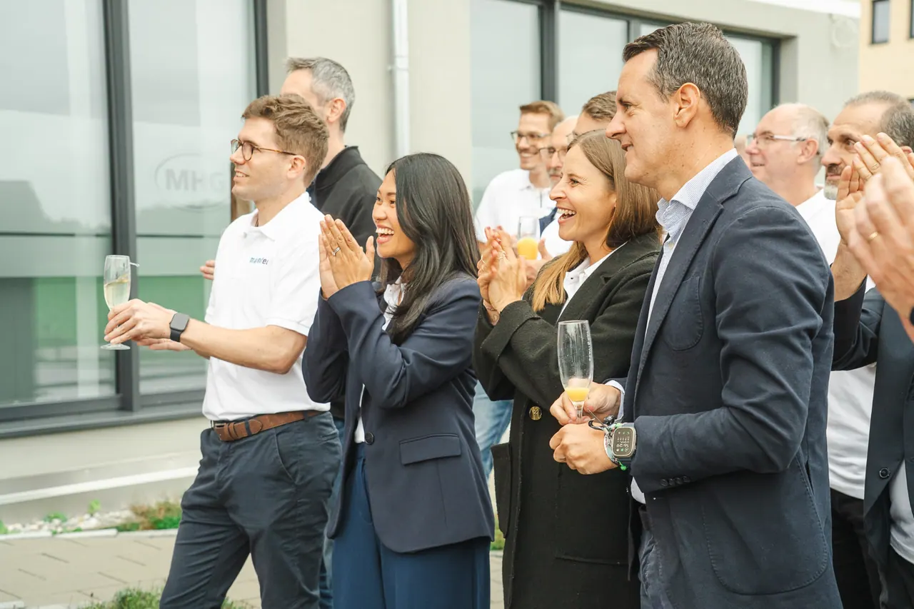 Manntech/Alimak Büroeröffnung — Applaudierendes Team mit Sektgläsern