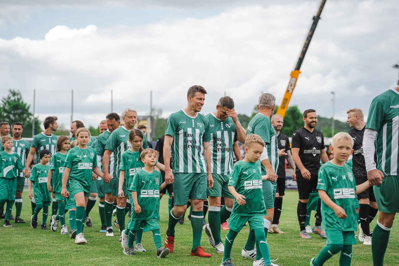 R+V Herzmomente 2025 — Lachende Spieler beim Einlauf mit Einlaufkindern in grünen Trikots