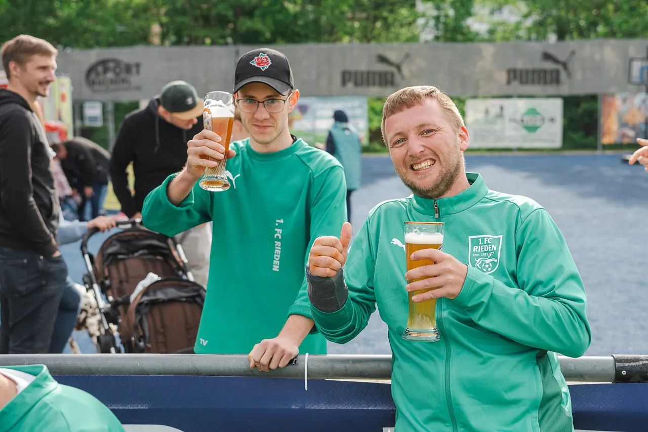 R+V Herzmomente 2025 — Zwei Spieler des 1. FC Rieden prosten mit Weißbier in die Kamera