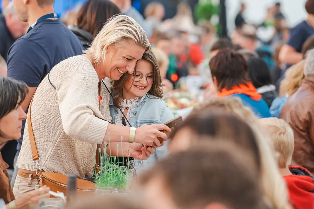 R+V Herzmomente 2025 — Mutter und Tochter lachen gemeinsam auf ein Smartphone-Display