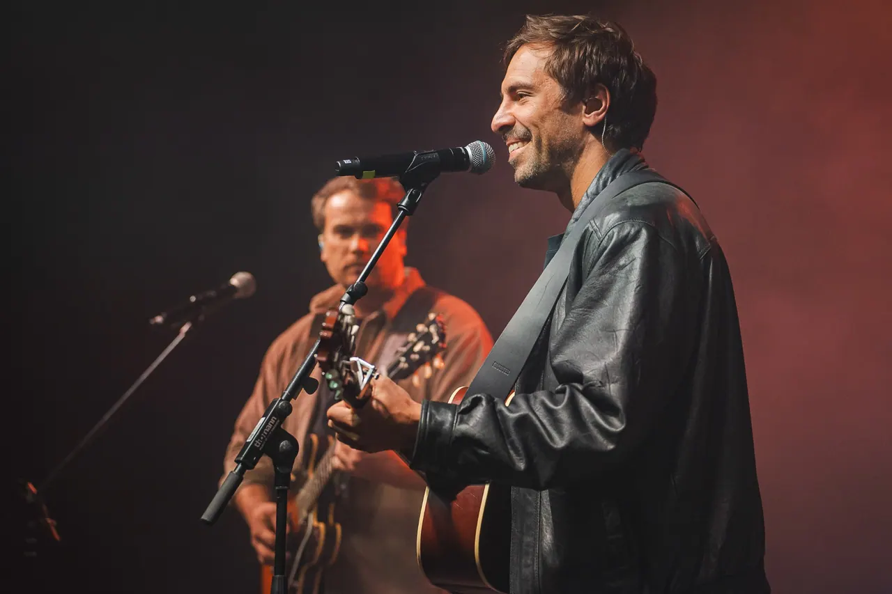 R+V Herzmomente 2025 — Sänger mit Akustikgitarre auf der Bühne im roten Bühnenlicht