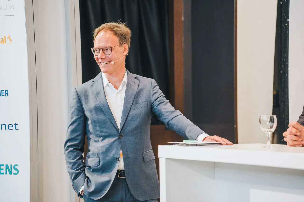 Agritech - Berlin Institute — Lächelnder Speaker im grauen Anzug mit Headset auf der Bühne